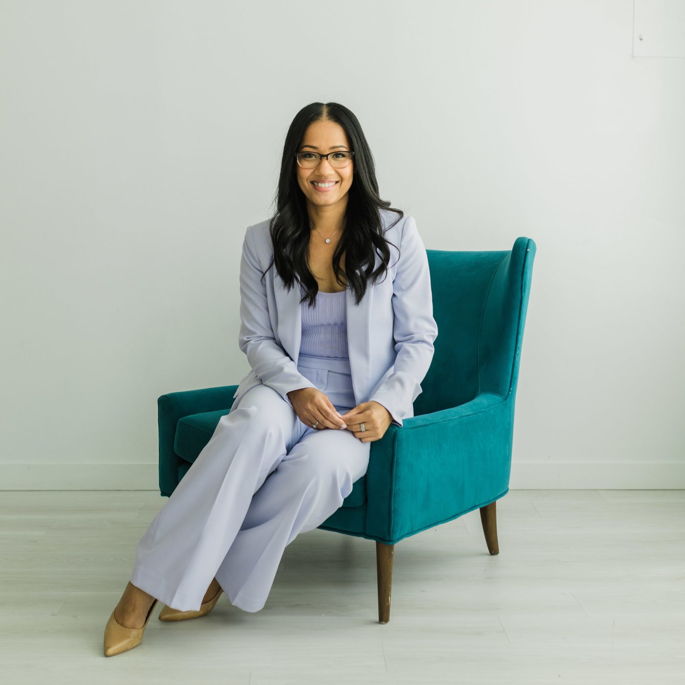 Dr. Sheena Glover seated in a teal armchair